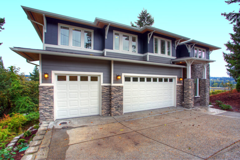 Home exterior with stone veneer siding, stone porch columns, and garage entry