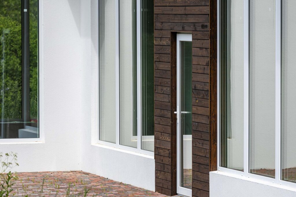 Modern home exterior with white stucco finish, large windows, and dark wood cladding